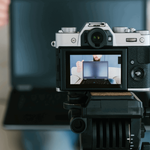 a man filming a laptop review and recording himself on a camera