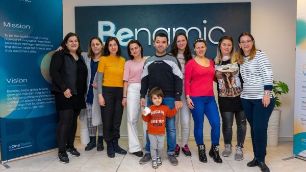 a group of employees with a child celebrating in front of Benamic sign in New hybrid Office.