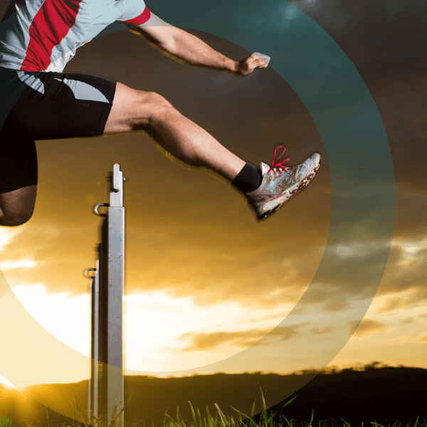 a man jumping over a hurdle on a field in sunset 