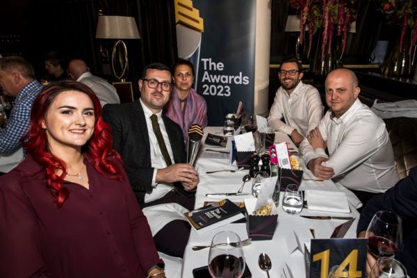 Benamic employees sitting & smiling at the camera on IPM Awards night.