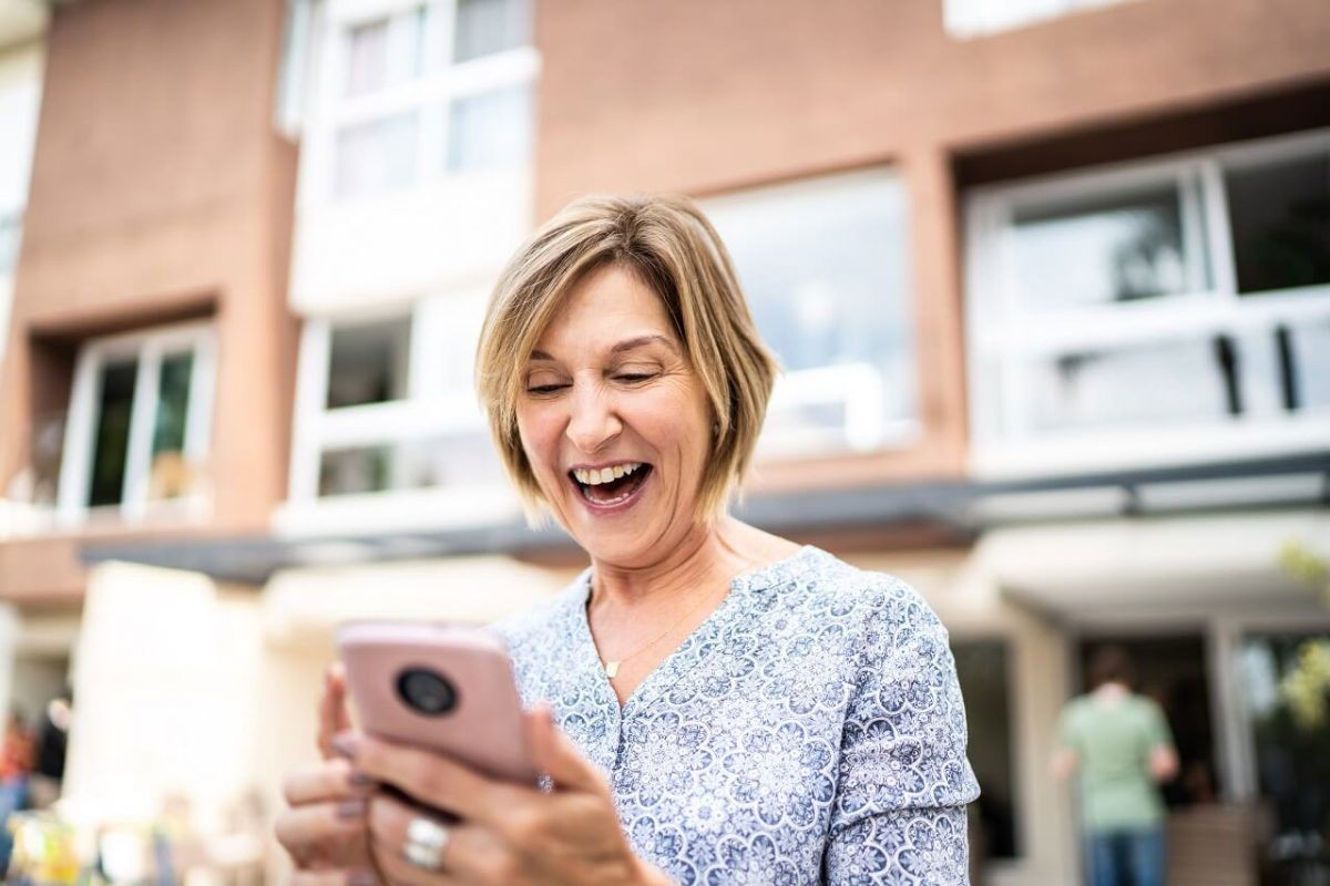 a senior woman looking at her phone in delight