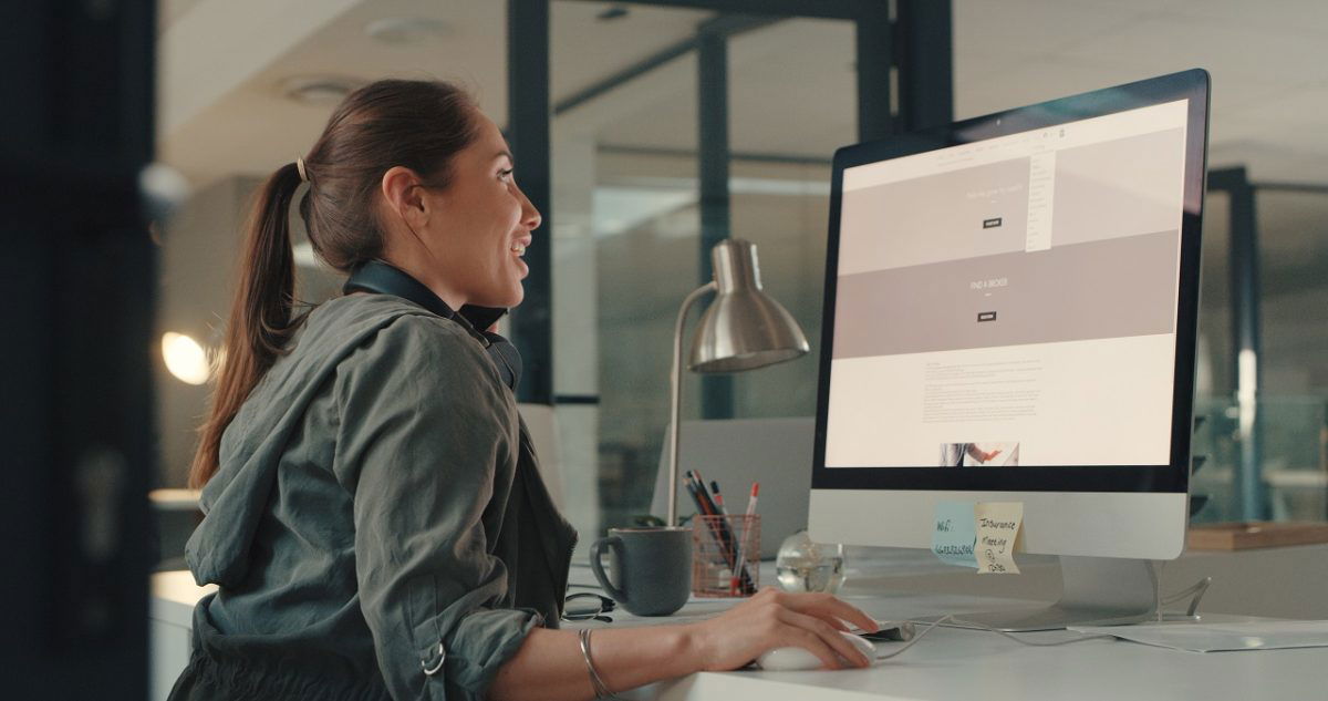 Shot of a young designer talking on a cellphone while working on a computer in an office